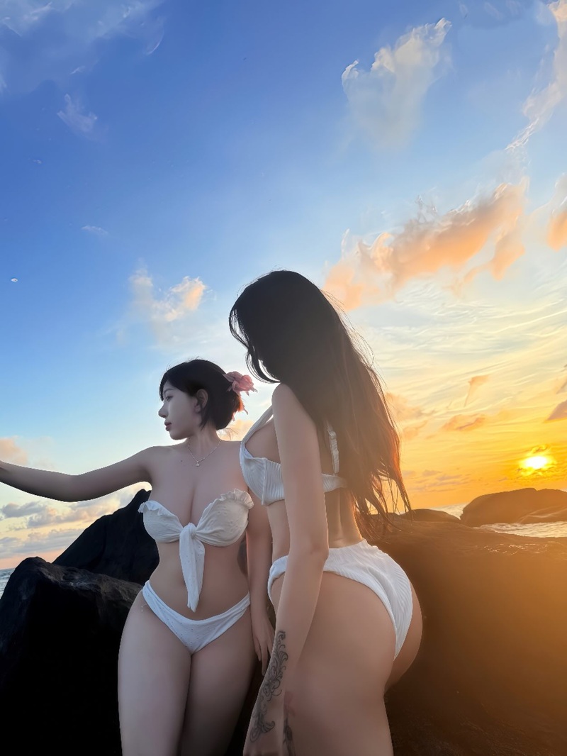 Cô gái mặc bikini trắng ngồi ngắm hoàng hôn bên bãi biển