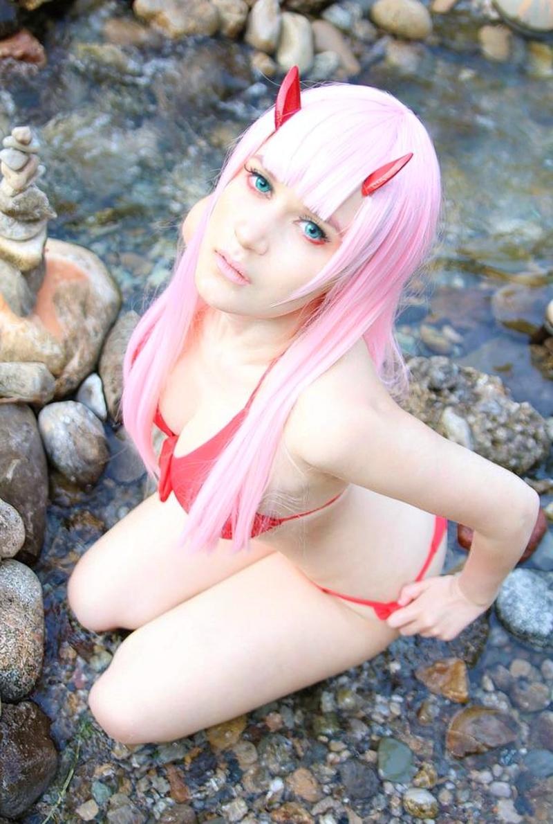 Zero Two pose ngồi nghiêng trên ghế pilot